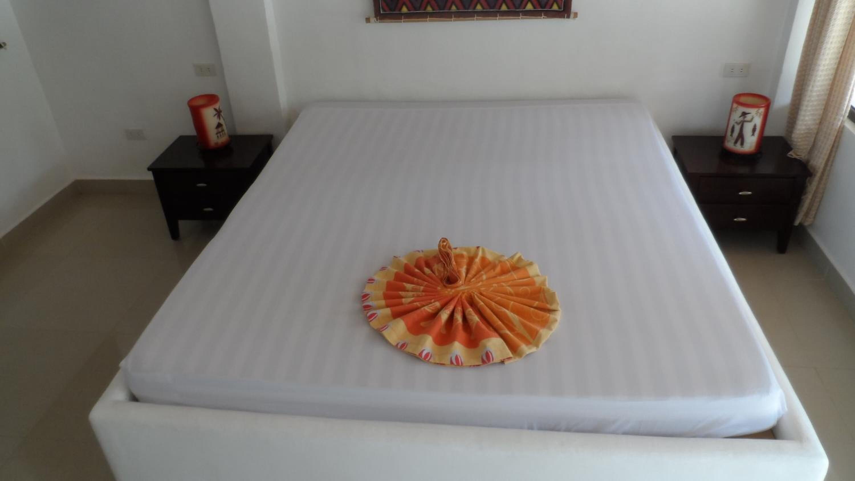 A bedroom with a large bed, two nightstands, and a decorative fan on the bed.