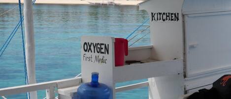 A boat's kitchen area with a sign labeled "OXYGEN First Medic" and a large blue oxygen cylinder.