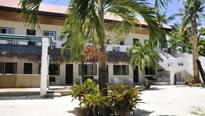 A building with a thatched roof, white walls, and a covered outdoor seating area. - Little Mermaid Dive Resort (Daanbantayan)