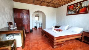 A hotel room with a bed, a desk, and a bathroom visible through an archway. - Little Mermaid Dive Resort (Daanbantayan)