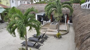 A beachside area with thatched-roof structures, palm trees, and lounge chairs. - Little Mermaid Dive Resort (Daanbantayan)