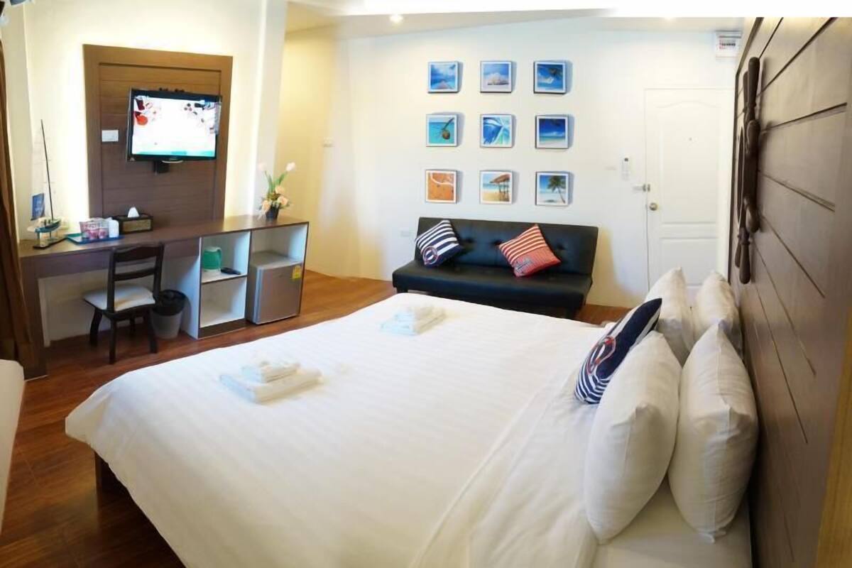 A hotel room with a bed, a desk, a chair, a television, and a wall with framed pictures.