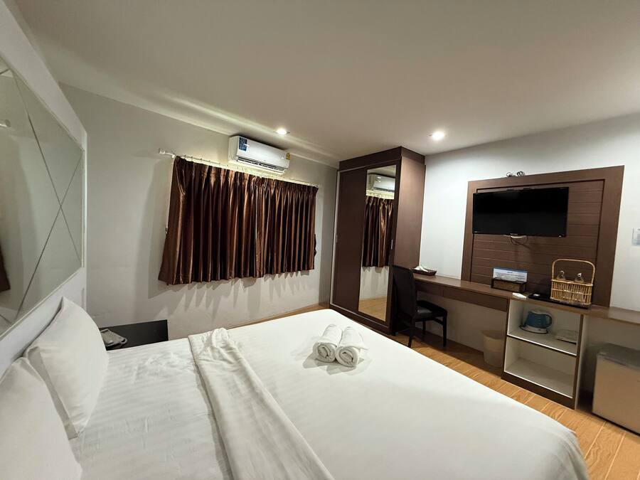 A hotel room with a bed, a desk with a chair, a TV, and a mirror.