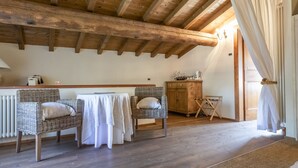 A cozy room with wooden beams, wicker furniture, a table, and a radiator.
