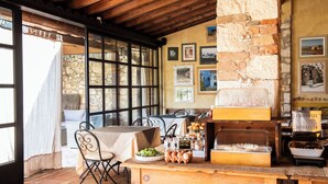 A rustic dining area with a stone wall, wooden beams, and a buffet table with food items.