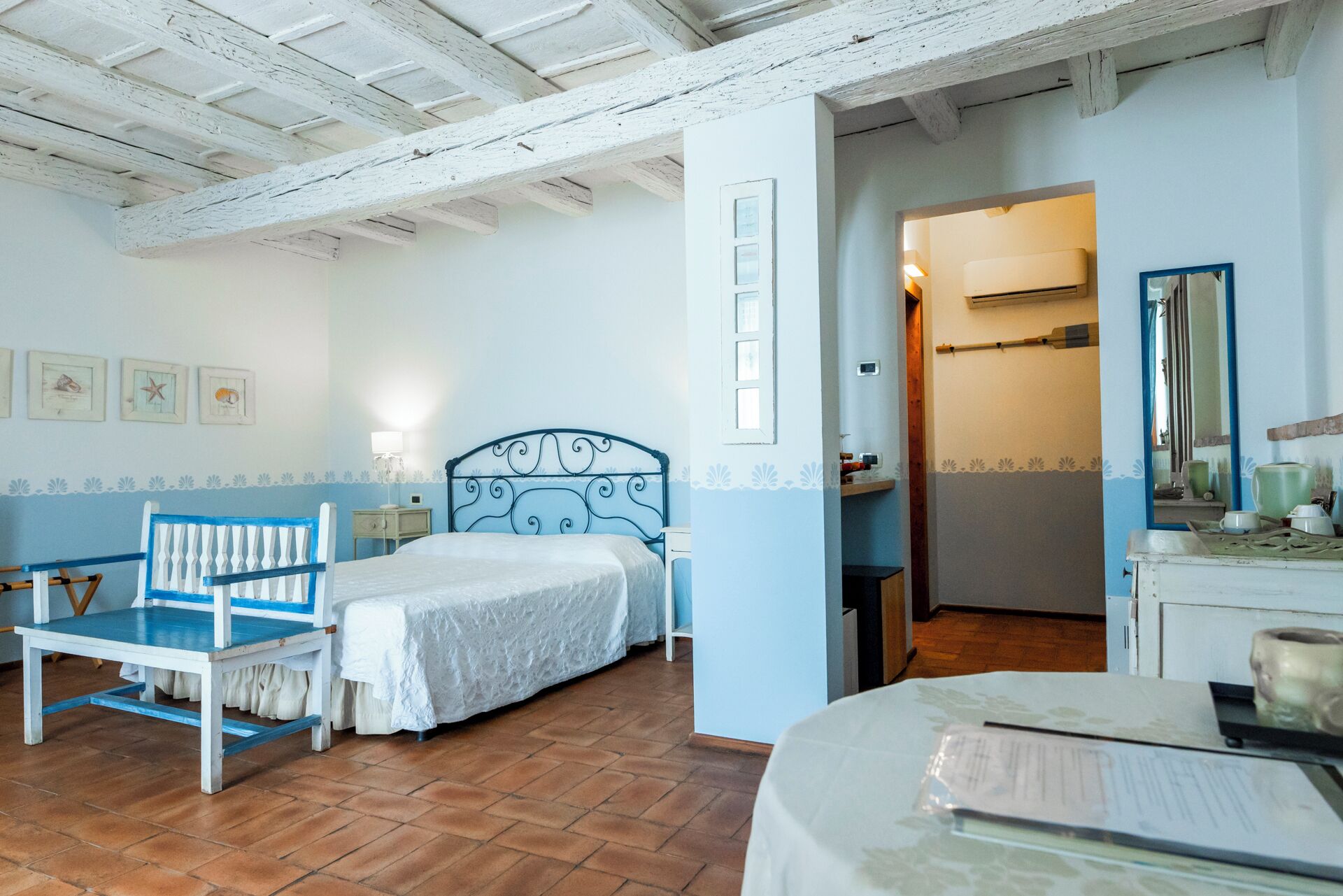 A bedroom with a bed, a chair, a dresser, and a mirror.