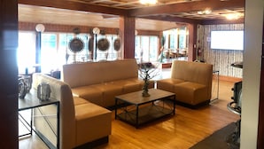 Un amplio salón con techo de madera, un sofá, una mesa de centro y un ventanal con diseños de rayos de sol decorativos.