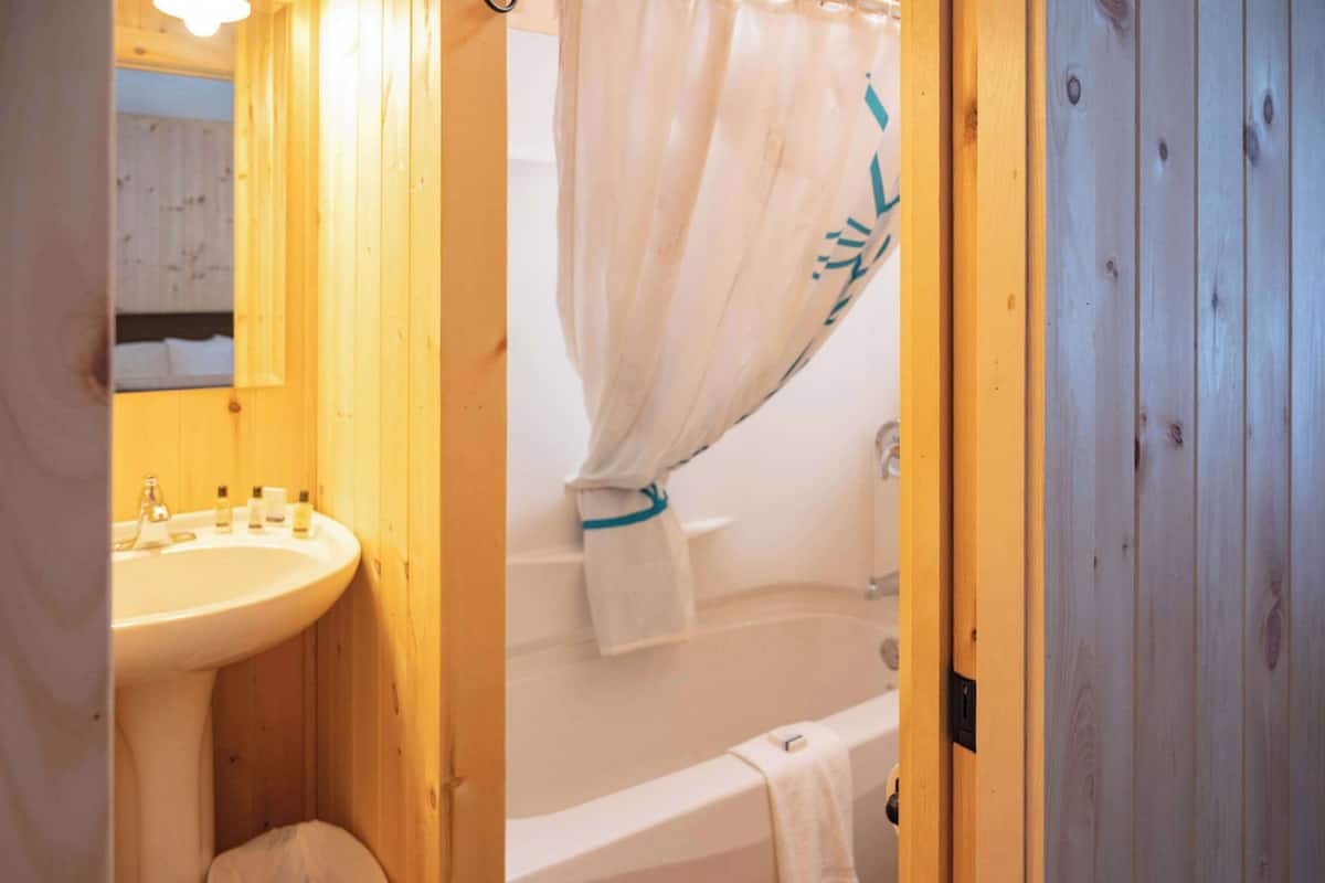 Ein Badezimmer aus Holz mit Waschbecken, Toilette und Badewanne.