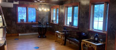 A spacious room with hardwood flooring, large windows, a chandelier, and a fireplace.