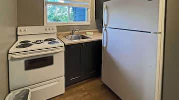 A compact kitchen with a stove, oven, sink, and refrigerator.