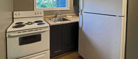 Una cocina compacta con estufa, horno, lavaplatos y refrigerador.