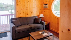 Una habitación acogedora con detalles de madera, un sofá, una mesita y una ventana.