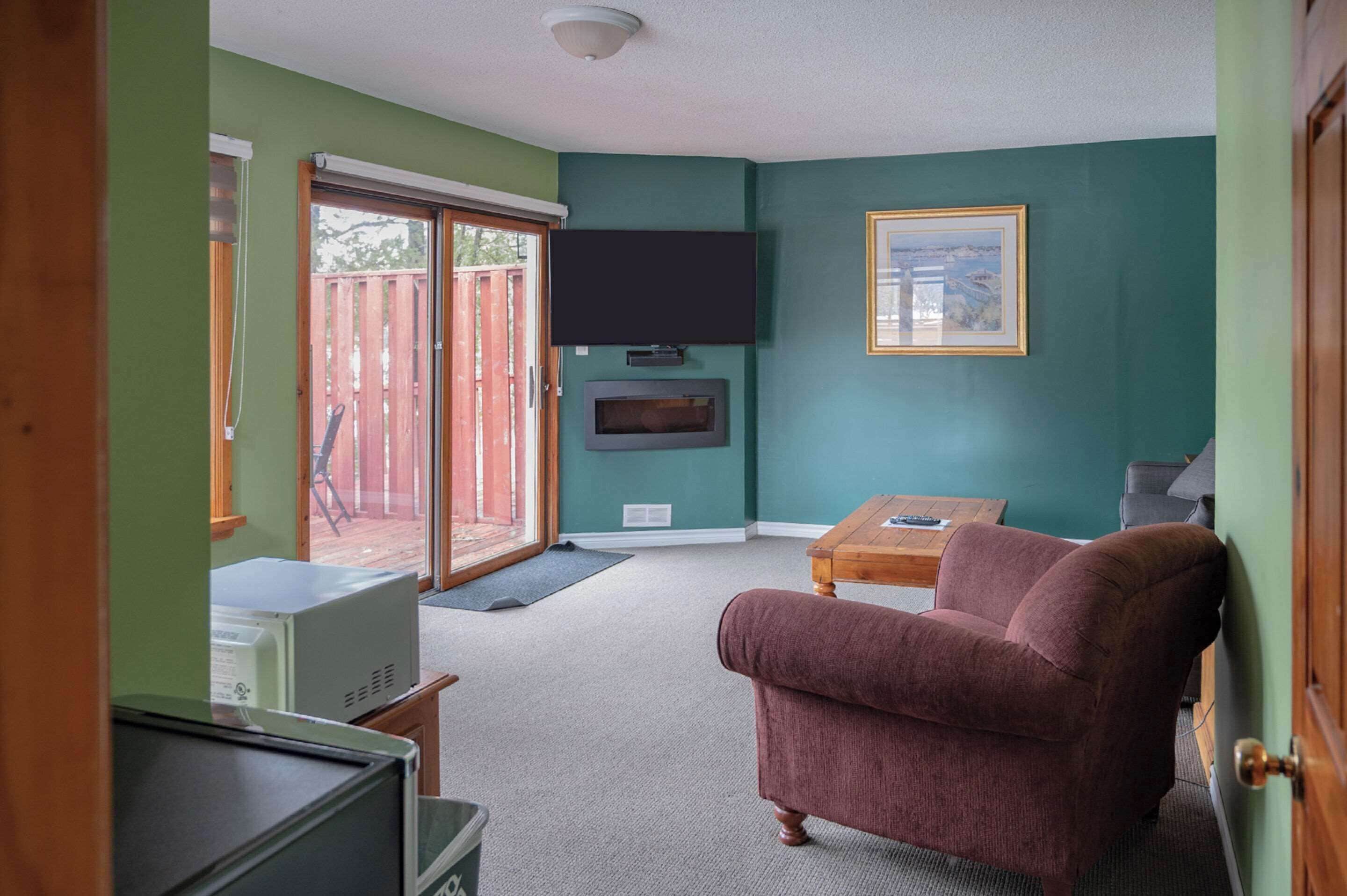 A living room with a television, a fireplace, a couch, and a sliding glass door to the outside.