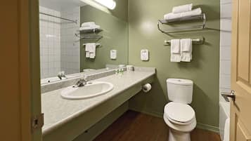 Un bagno con lavandino, specchio, water e porta asciugamani.