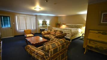 Ein Hotelzimmer mit einem Bett, zwei Sesseln, einem Sofa, einem Holztisch, einem Nachttisch und einer Lampe.