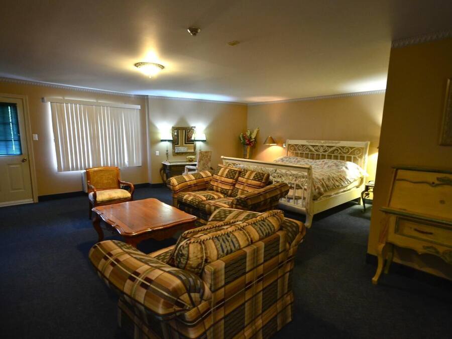 Ein Hotelzimmer mit einem Bett, zwei Sesseln, einem Sofa, einem Holztisch, einem Nachttisch und einer Lampe.