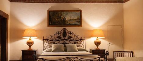 Un dormitorio con una cama, dos mesitas de noche con lámparas, una puerta y un techo con un diseño decorativo.