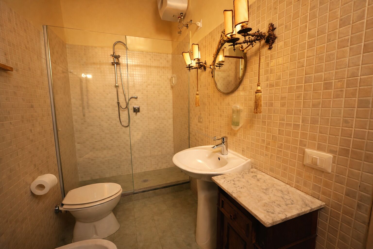 Une salle de bain avec une douche à parois de verre, des toilettes, un lavabo et un meuble-lavabo avec un miroir.