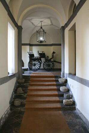 Un escalier recouvert d’une moquette marron, avec des marches en pierre et une lanterne suspendue.