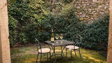 A stone wall with a small table and chairs in a garden area.