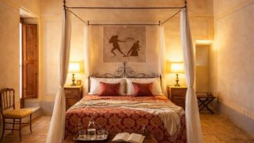 A traditional bedroom with a four-poster bed, a wooden ceiling, and a stone floor.