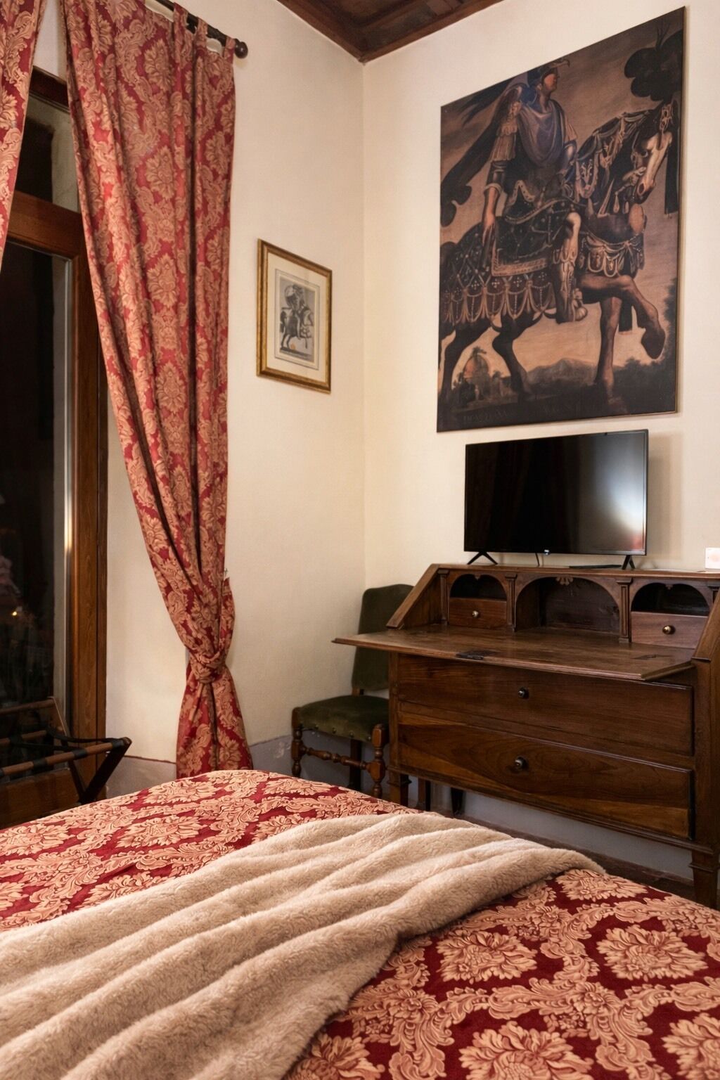 Quarto com cama, cómoda de madeira, televisão e um quadro na parede.