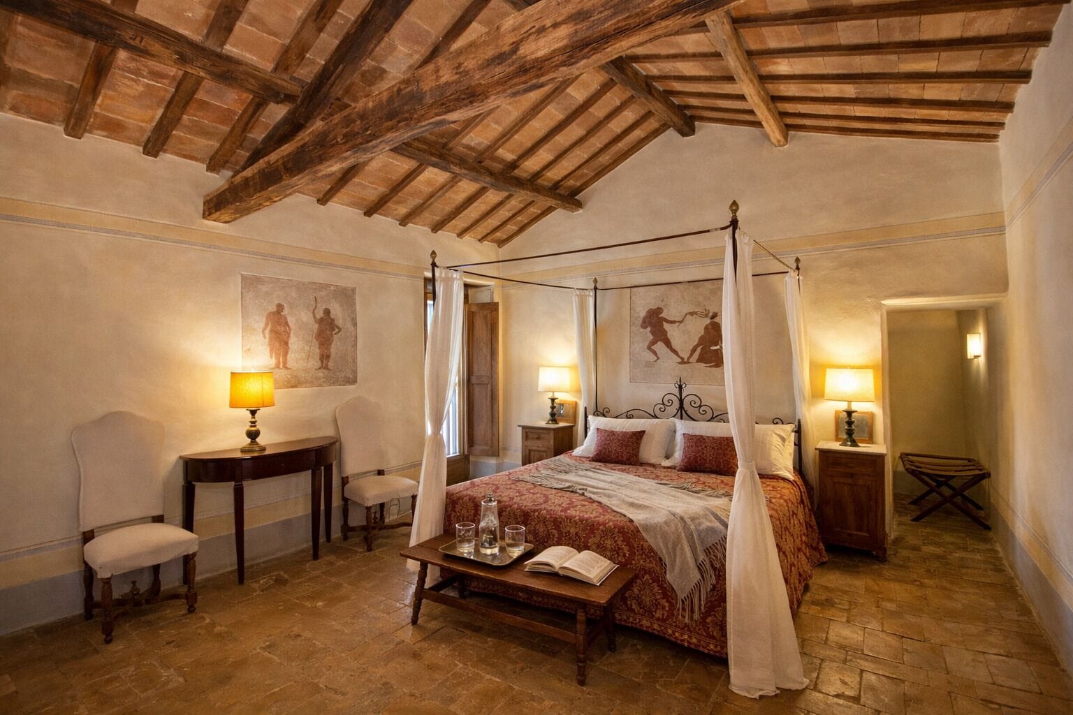 Ein Himmelsbett mit roten und weißen Bettbezügen, ein Nachttisch mit einer Lampe und ein Sessel.