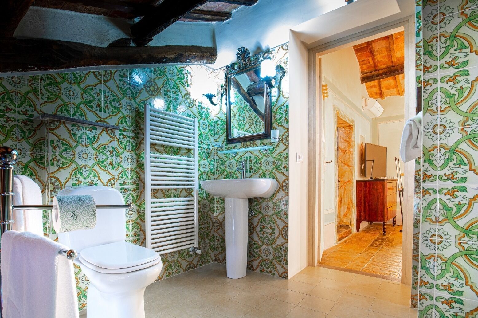 A bathroom with patterned tiles, a white sink, a toilet, and a towel rack.