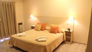 A hotel room with a large bed, two bedside tables, and a nightstand with a lamp.
