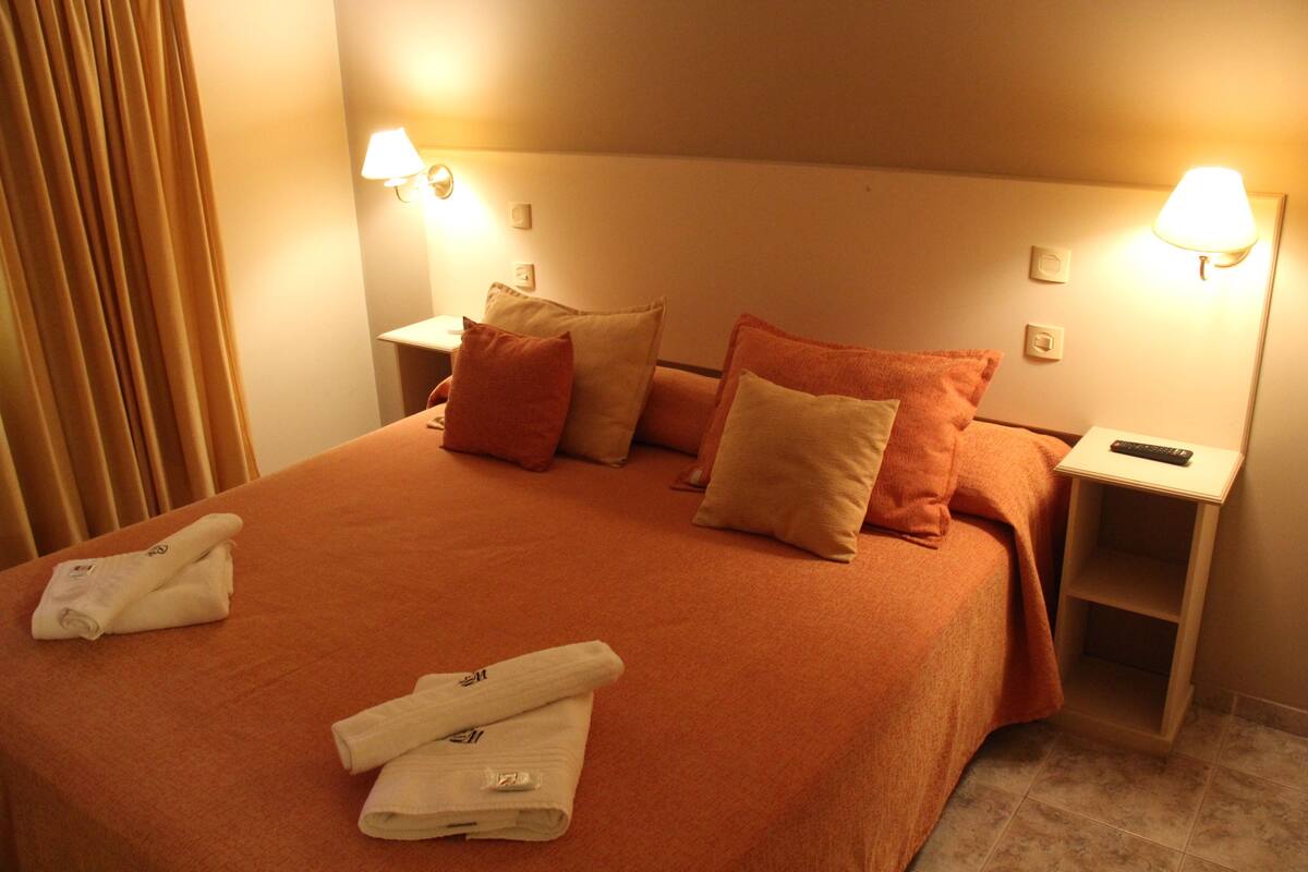 Une chambre d’hôtel avec un grand lit, deux tables de chevet et une petite table d’appoint.