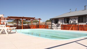 A swimming pool with a pergola and outdoor seating area.
