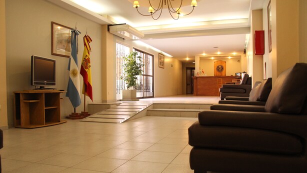 A hotel lobby with a reception desk, seating area, and flags.