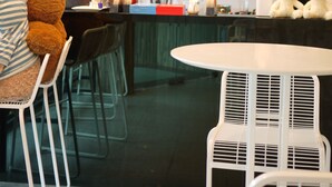A modern kitchen with dark cabinets, a coffee machine, and a teddy bear on the counter. - Triple 8 Inn Bangkok (Bangkok)
