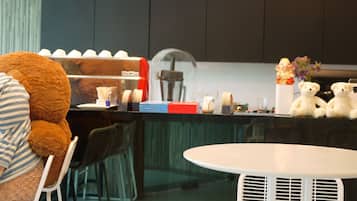A modern kitchen with dark cabinets, a coffee machine, and a teddy bear on the counter.