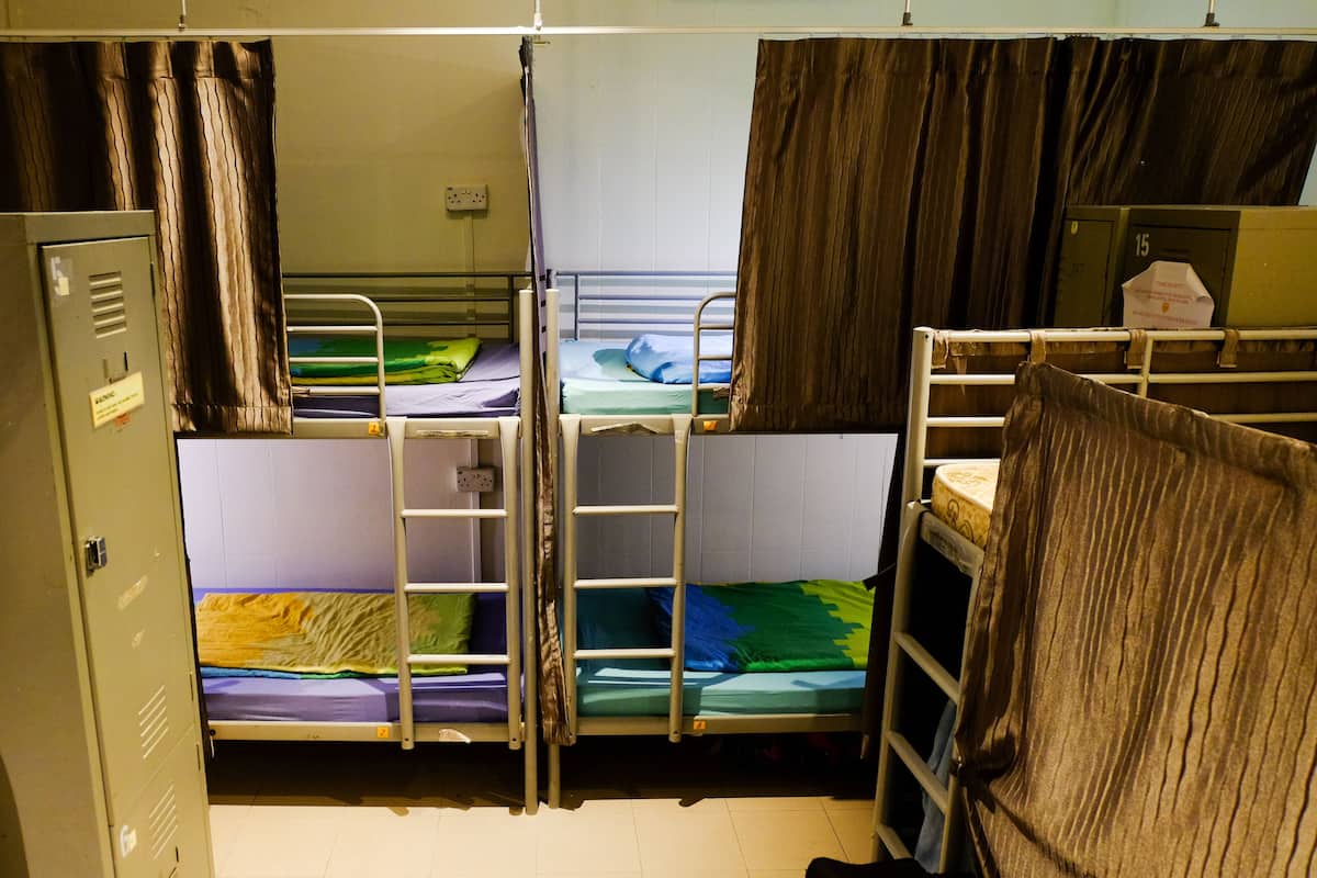 A dormitory room with bunk beds, a wardrobe, and a curtain.