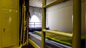 A dormitory room with bunk beds, a wardrobe, and a window with a metal grid. - Fernloft Chinatown - Hostel (Singapore)