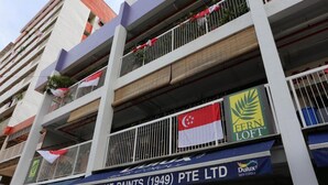 A multi-story building with balconies, flags, and signage for a paint store. - Fernloft Chinatown - Hostel (Singapore)