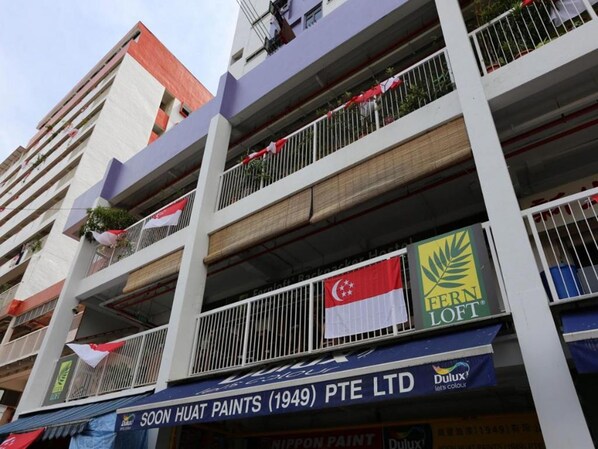 A multi-story building with balconies, flags, and signage for a paint store.