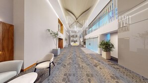 A modern hotel lobby with a patterned carpet, seating area, and a reception desk.