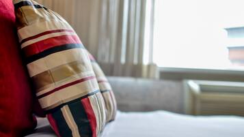 A bed with striped pillows and a red pillow.