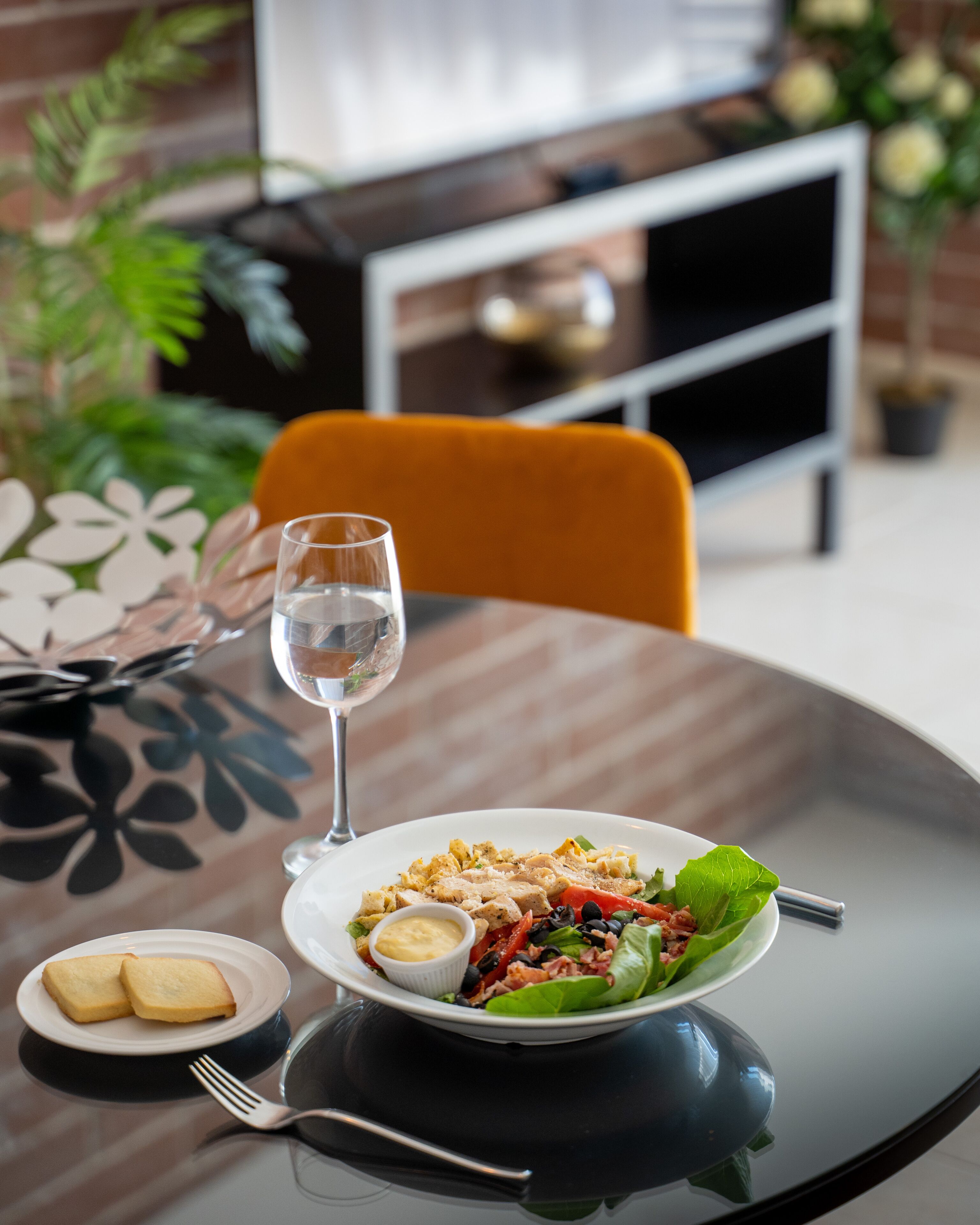 A dining table with a plate of food, a glass of water, and a fork.
