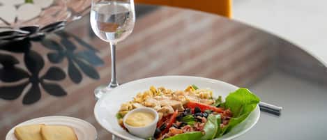 A dining table with a plate of food, a glass of water, and a fork.