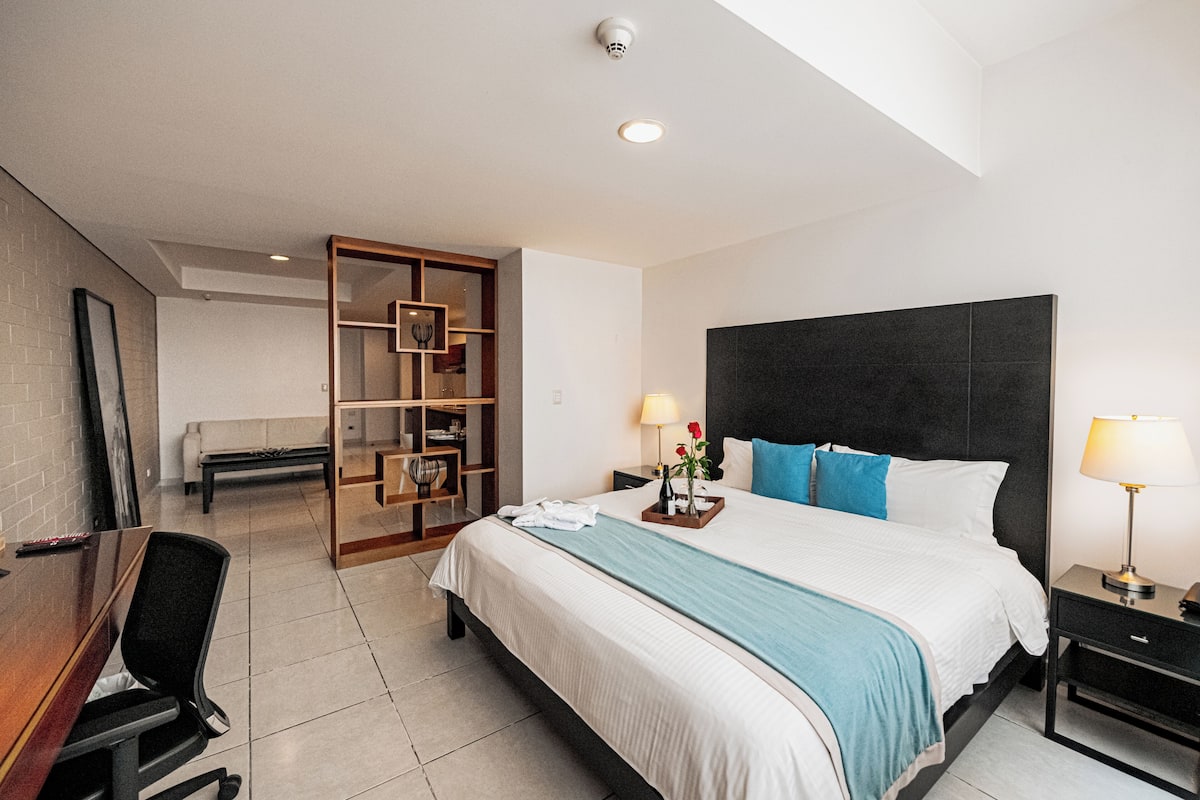 A hotel room with a bed, bedside tables, a desk, and a chair.