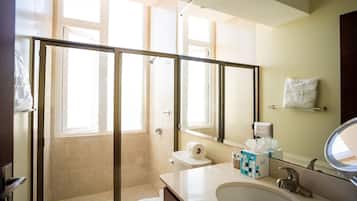 A modern bathroom with a glass shower enclosure, a toilet, a sink with a mirror, and a towel rack.