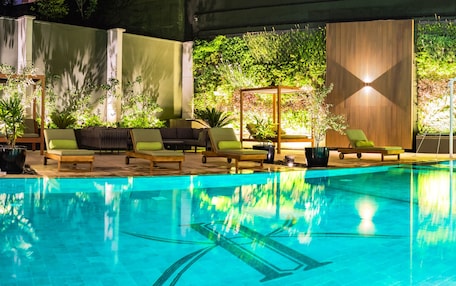 An indoor swimming pool with lounge chairs and a wooden deck.