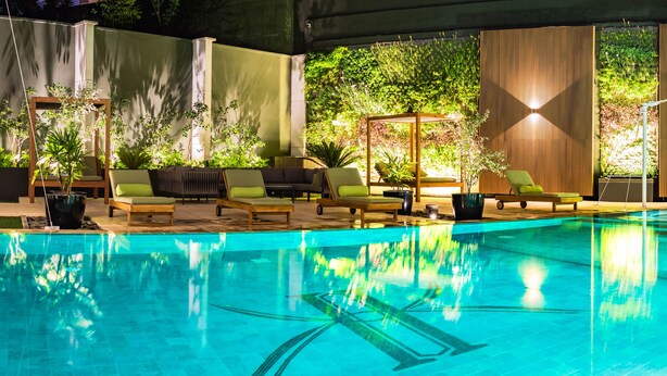 An indoor swimming pool with lounge chairs and a wooden deck.