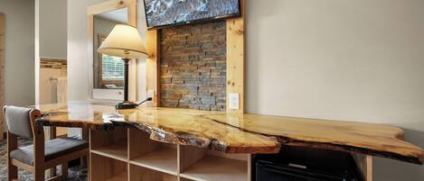 A wooden bar counter with a television mounted above it, a lamp, and a chair.