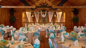 A banquet hall with round tables set for a formal event, featuring white tablecloths and teal sashes. - Caberfae Peaks Ski & Golf Resort (Cadillac)