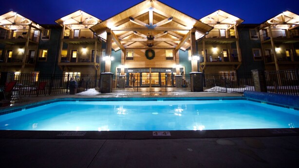 A hotel with a pool, wooden exterior, and a covered entrance area. - Caberfae Peaks Ski & Golf Resort (Cadillac)