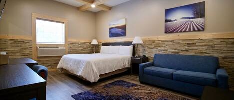A bedroom with a bed, a blue sofa, a desk, and a rug.